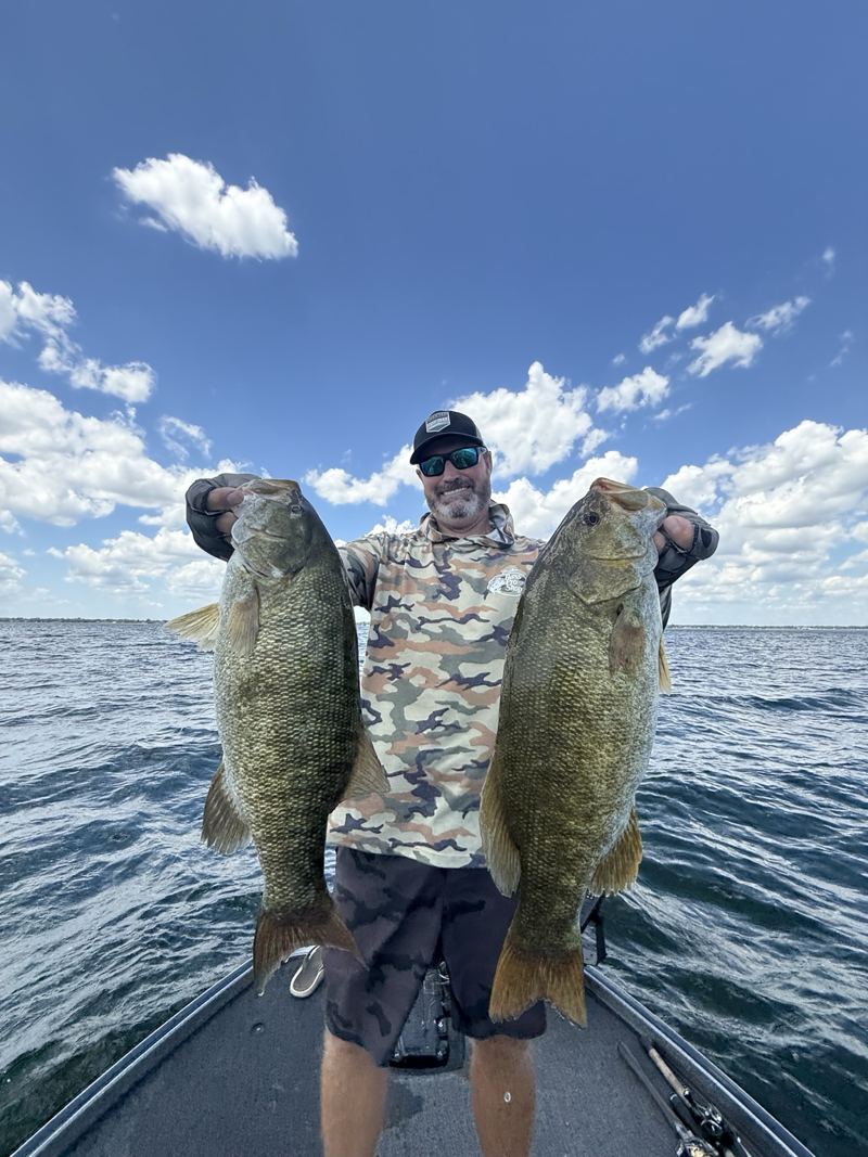 Brad holding two fish on a sunny day