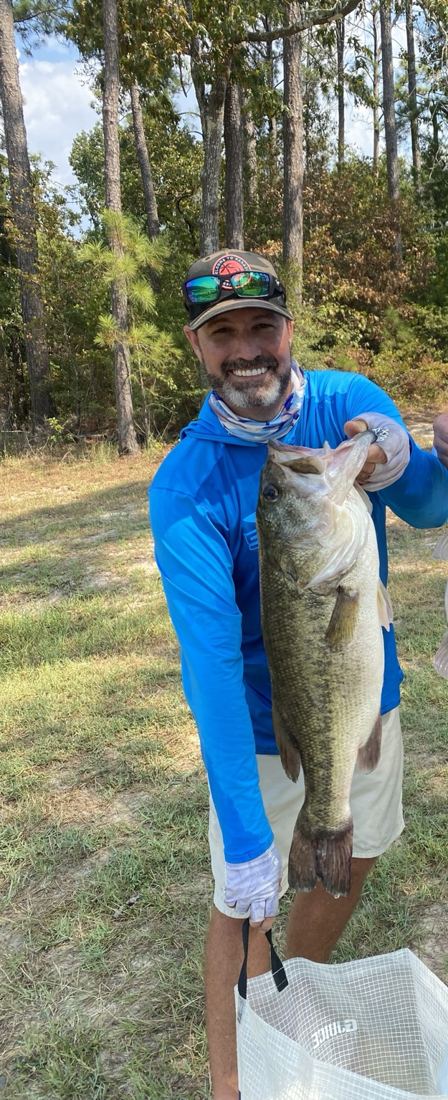 Brad holding a fish aboard a bass boat